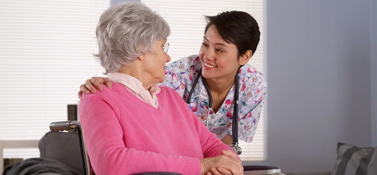 A healthcare worker helping a disabled patient with mobility support.